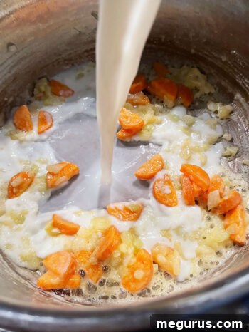 Milk being poured into the soup pot with broth and vegetables.