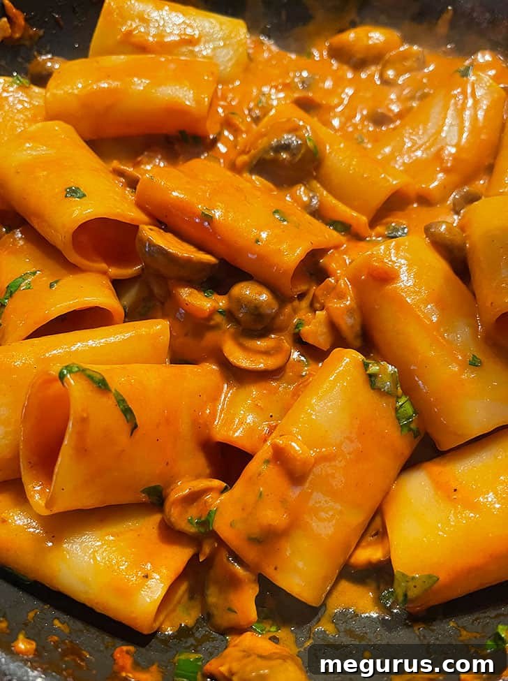 Close-up of mushroom ragù pasta being stirred until sauce evenly coats all noodles