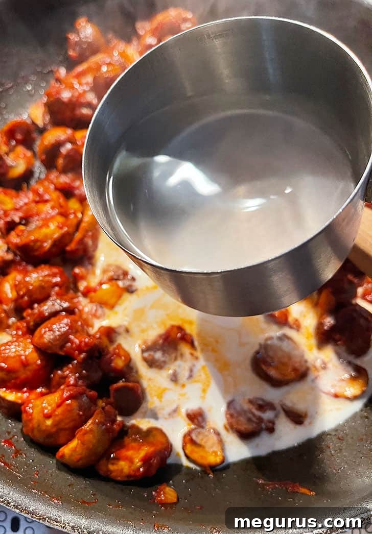 Reserved pasta cooking water being added to the mushroom ragù to create a creamy sauce