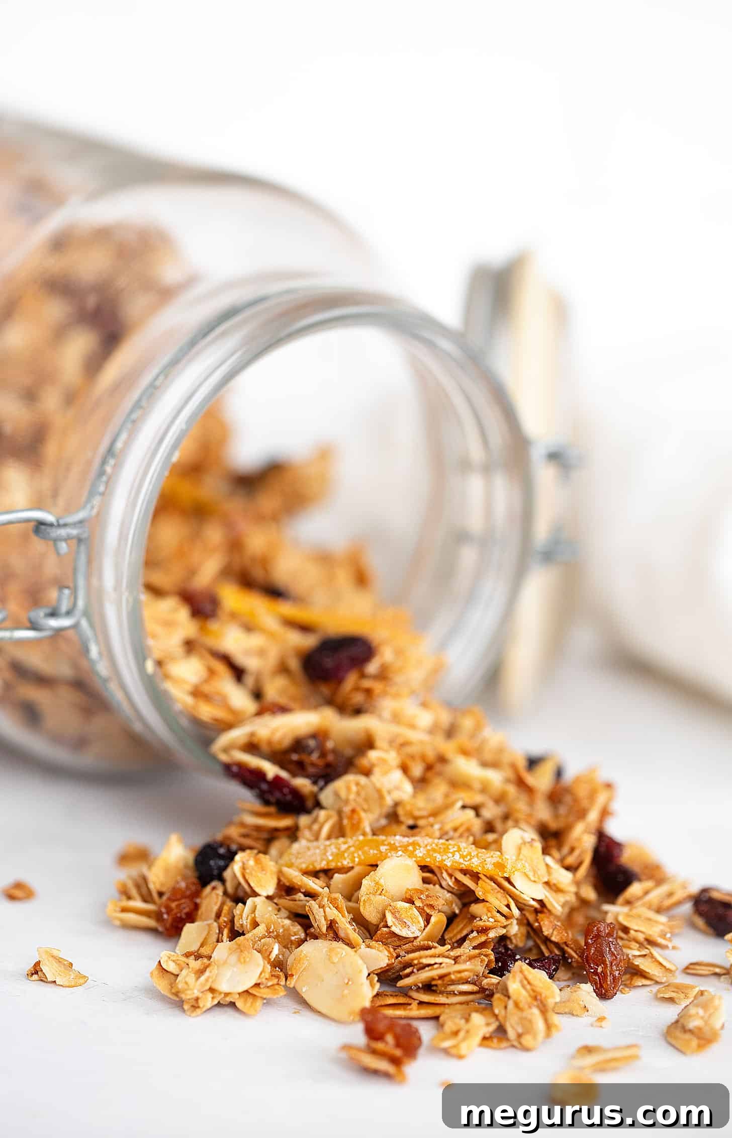 Abundant cranberry orange granola overflowing from a stylish clear glass container, showcasing its rich texture and wholesome ingredients.