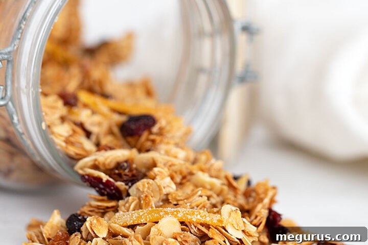 Cranberry orange granola spilling enticingly from a glass jar, ready for serving.