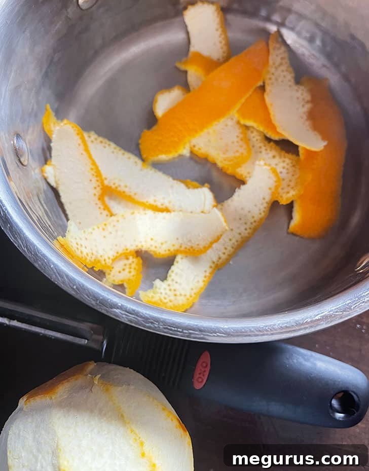 Thin strips of orange peel placed in a saucepan before boiling.