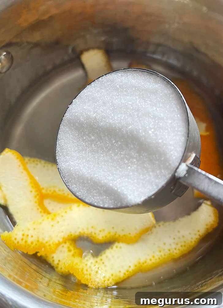Adding sugar to water in a saucepan, ready to create the candying syrup.