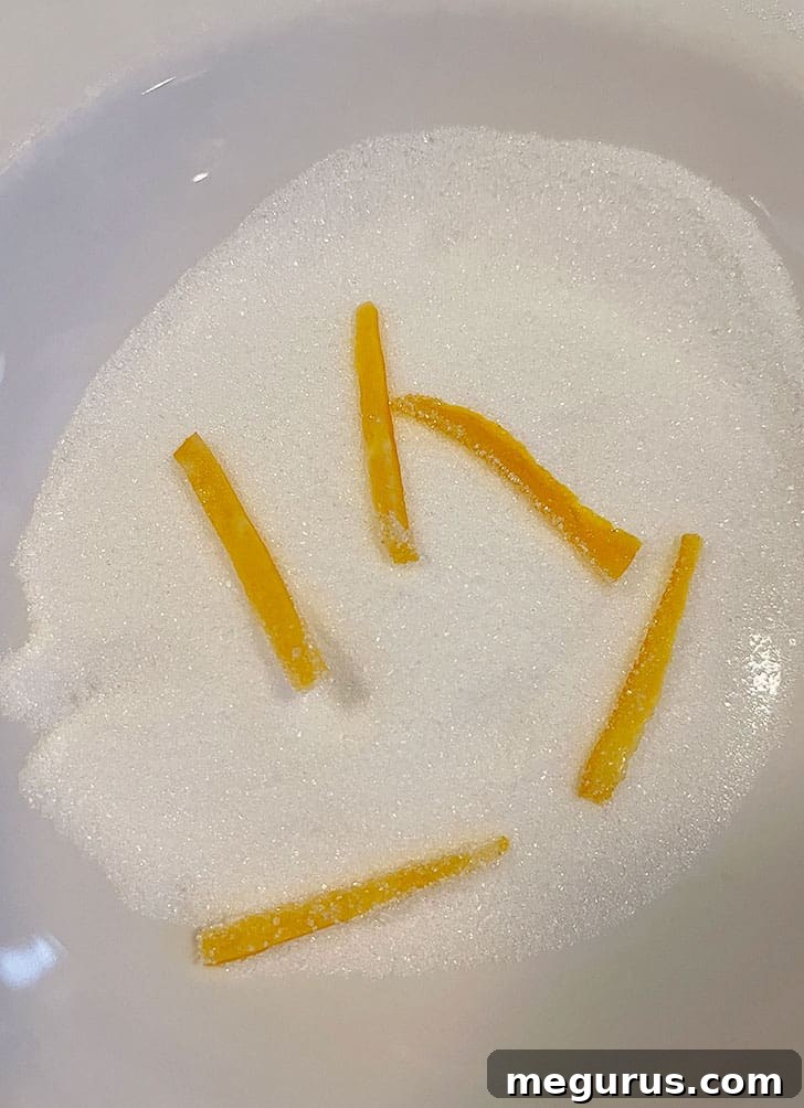 Orange peel pieces being tossed and coated evenly in white granulated sugar.