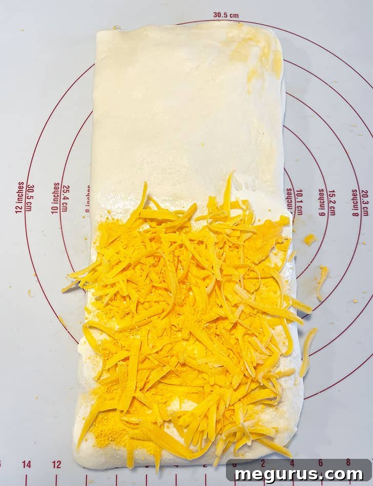 The last application of cheese being added to the dough before the final fold.