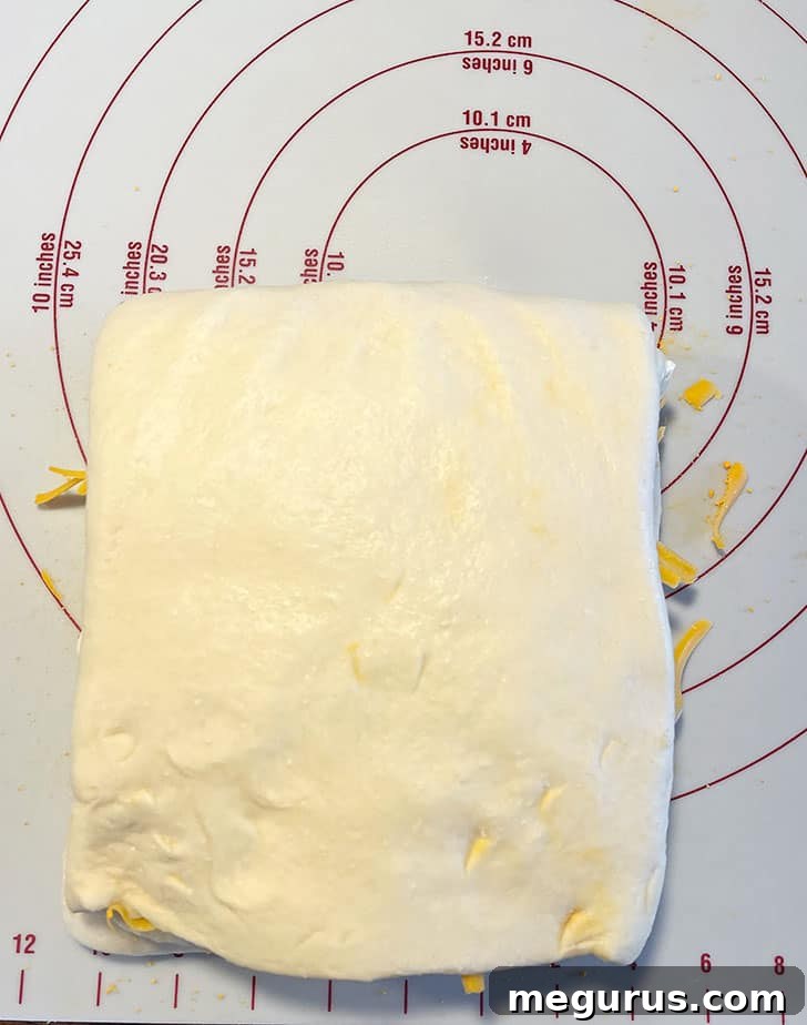 The top half of the dough being folded down to complete the layering process, creating a compact block.