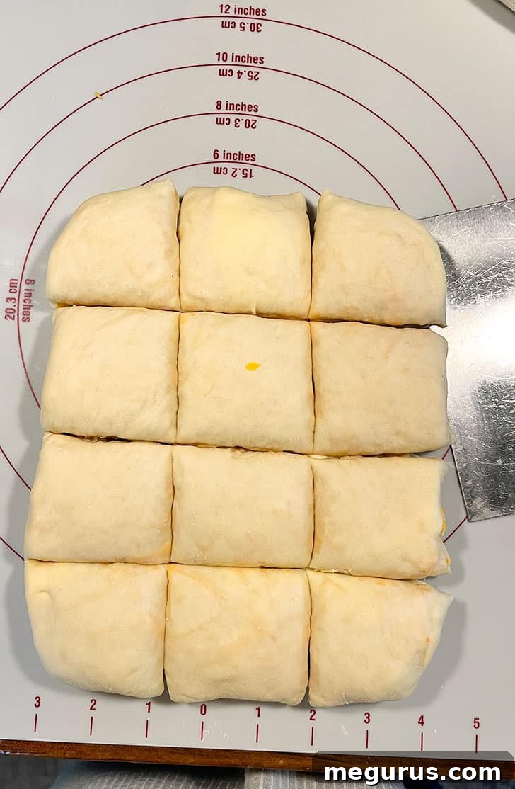 The layered dough being cut into 12 even square pieces for the buns.