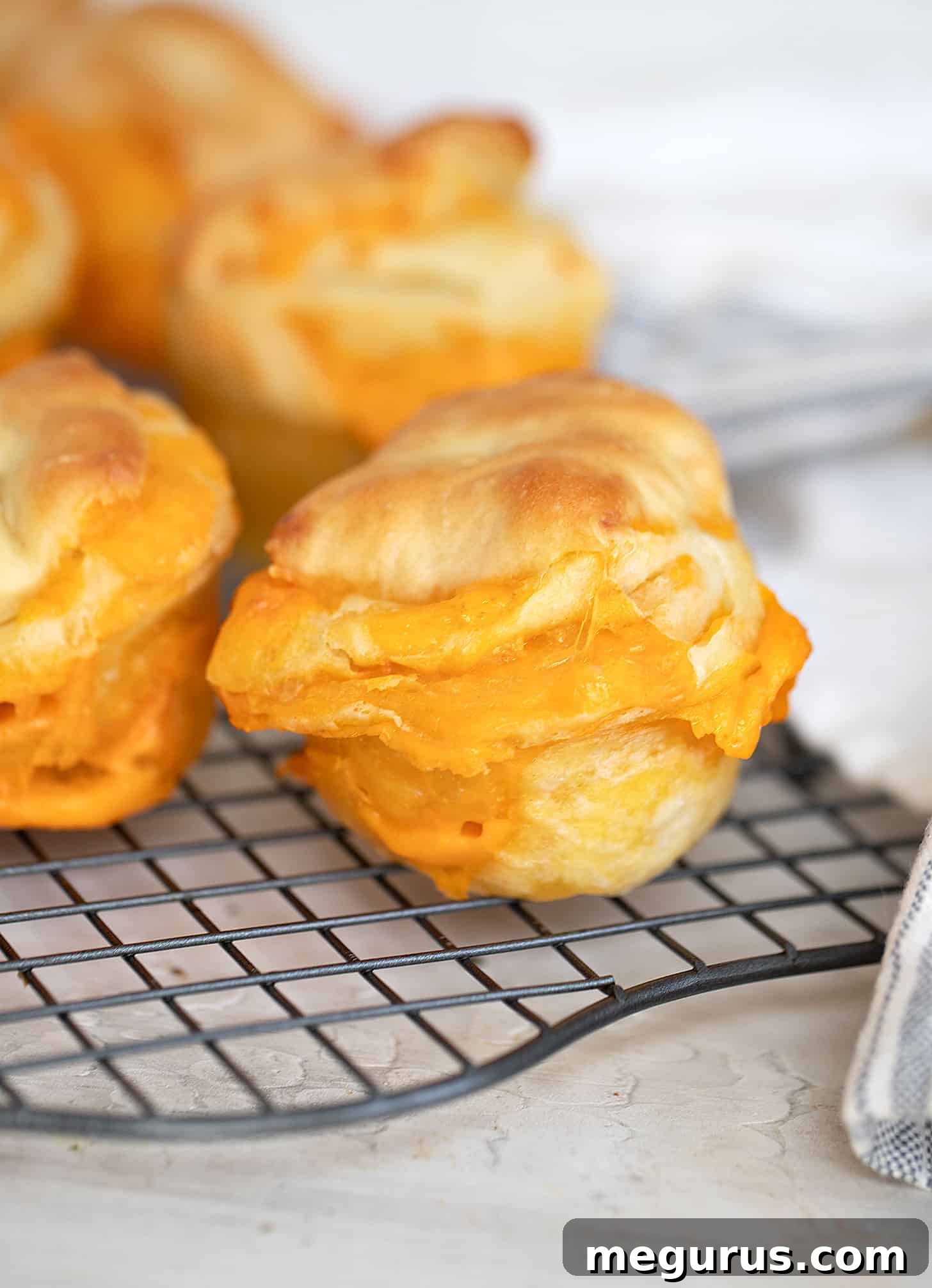 Close-up of baked golden brown cheese buns on a cooling rack, showing a perfect crust.