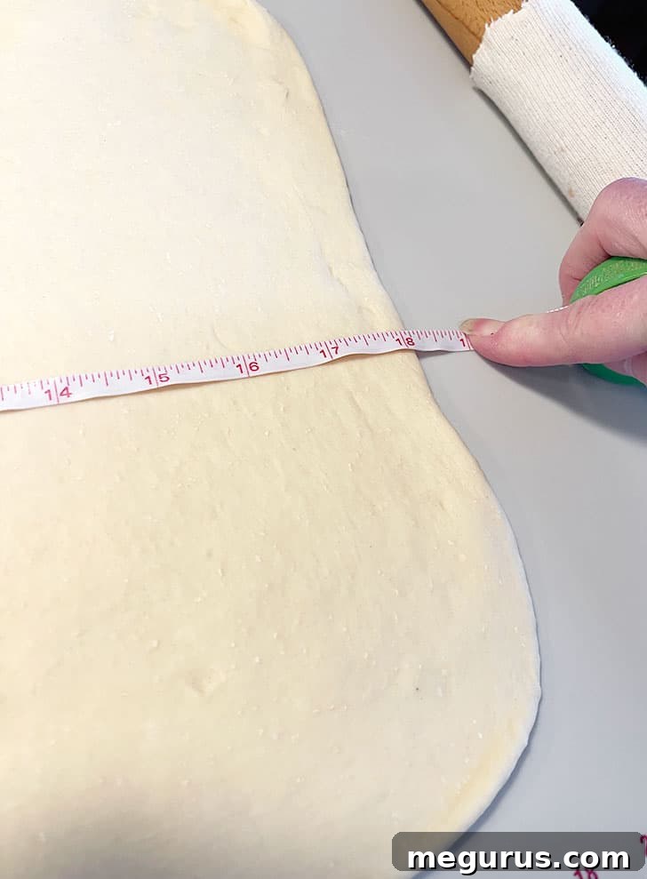 Measuring the dough rectangle to ensure proper dimensions before adding fillings.