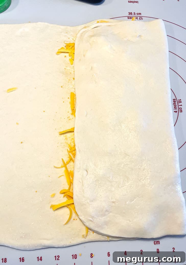 More softened butter being spread on the newly folded dough surface.