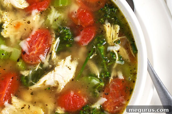 Chicken Pesto Soup in a simple white bowl with a spoon