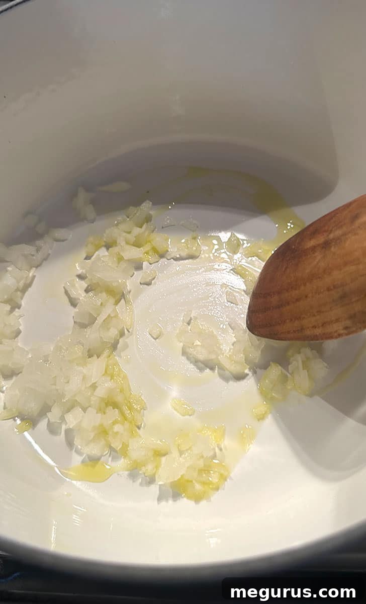 Sautéing diced onion in olive oil in a large pot until translucent.
