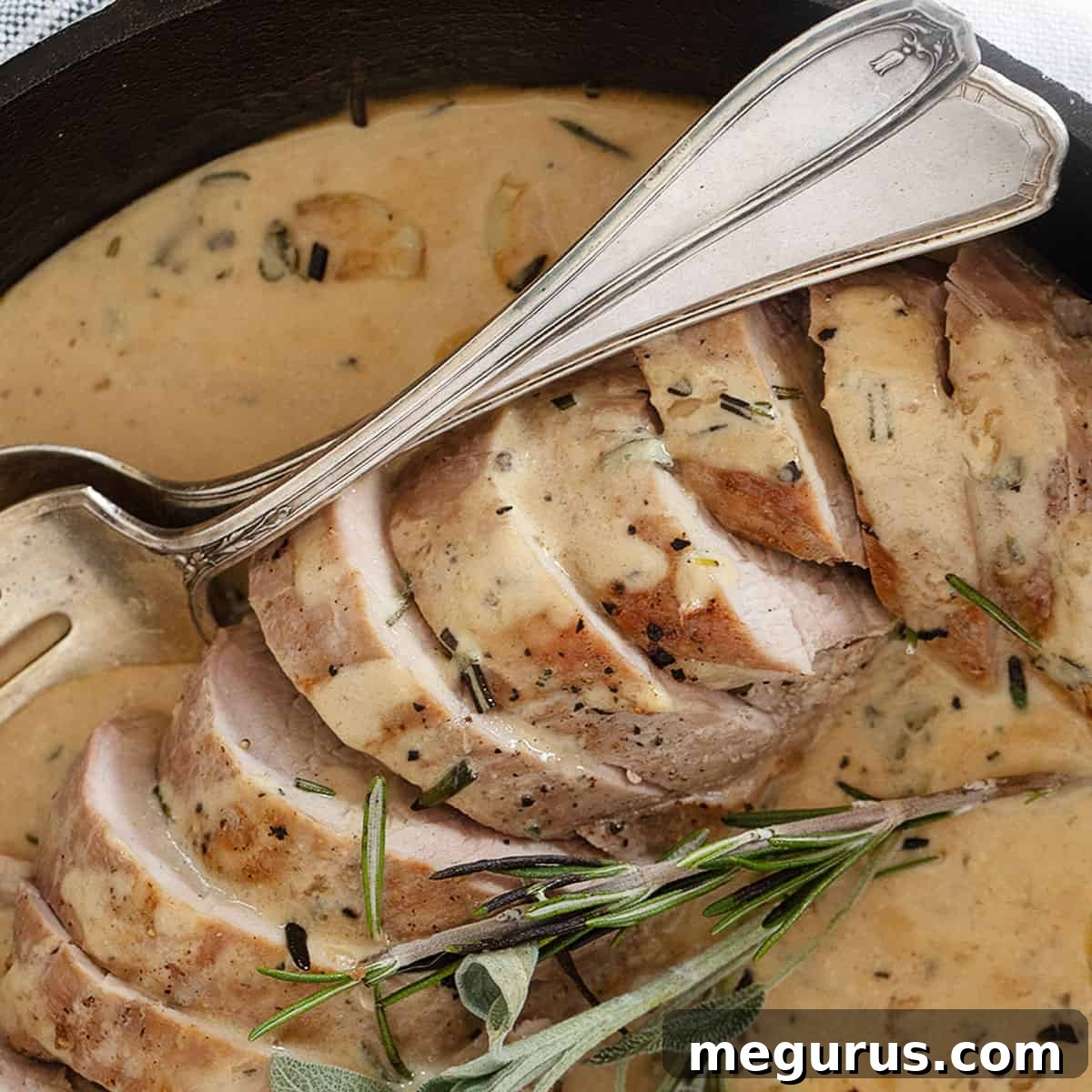 Pork tenderloin sliced in pan with creamy herb garlic sauce