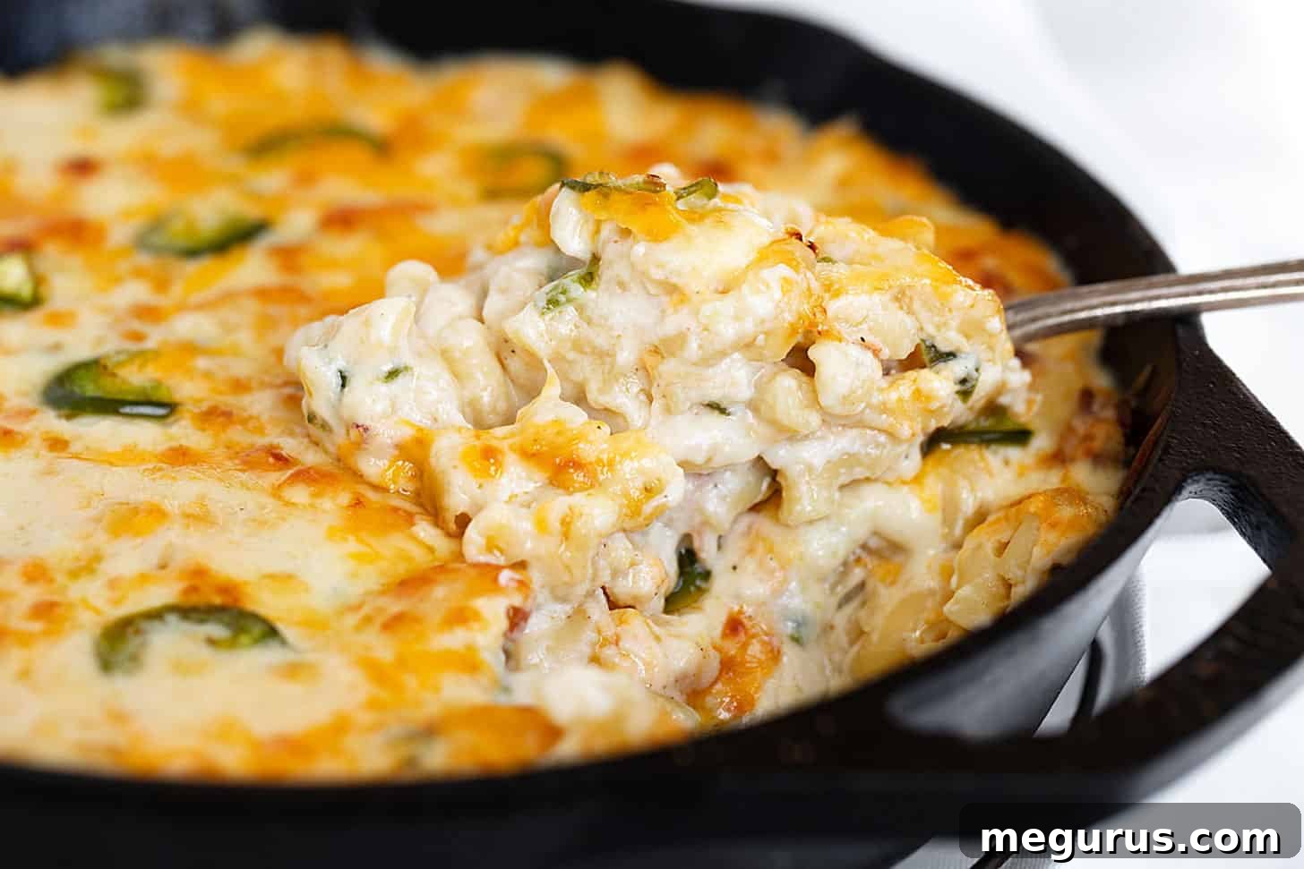 Generous serving of spicy jalapeño mac and cheese with bacon in a rustic cast iron skillet, ready to be enjoyed.