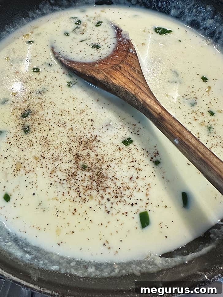 Milk being slowly whisked into the roux, forming a smooth and thickening béchamel sauce.