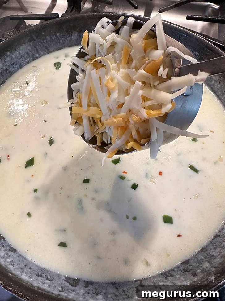 Shredded cheddar and cream cheese melting into the warm béchamel sauce, creating a rich and creamy cheese sauce.