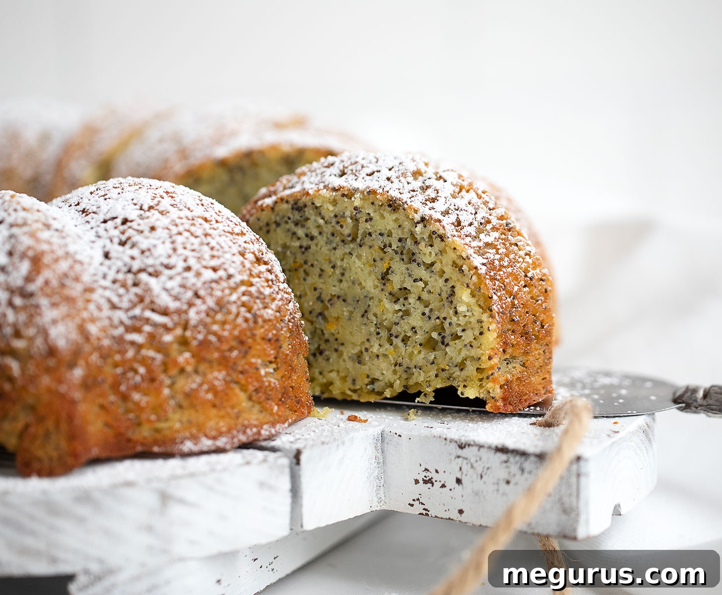 Slices of Orange Poppy Seed Bundt Cake arranged on a white serving board, showcasing its tender texture and poppy seed speckles.