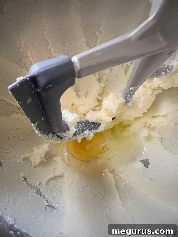 Adding eggs one by one to the mixture.
