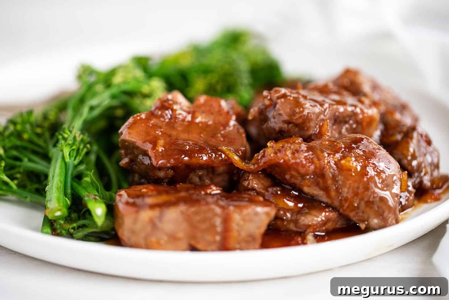 Tender orange pork medallions with a glossy ginger-orange sauce, served alongside fresh broccolini for a quick and vibrant dinner.