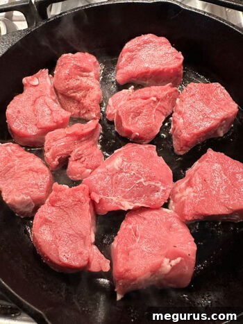 Pork medallions sizzling and browning in a hot skillet, developing a delicious crust.