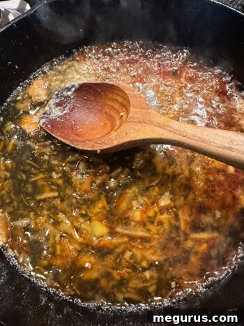 Sauce ingredients—orange marmalade, ginger, garlic, fish sauce, and lime juice—added to the same skillet where pork was cooked.