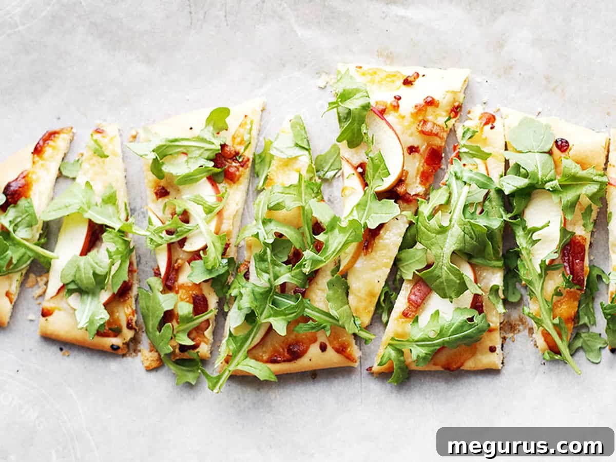 Delicious cheddar, pancetta, and apple flatbread on parchment paper, ready to be served.