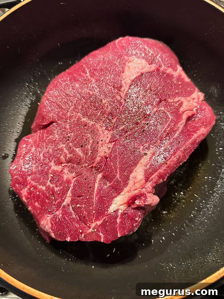 Searing a boneless chuck roast in a hot skillet until beautifully browned on all sides, the first crucial step in developing deep flavor for barbacoa.
