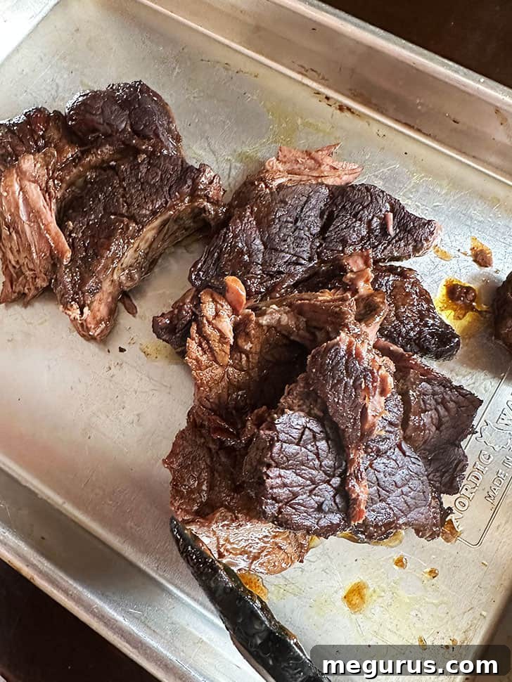 A perfectly cooked, fall-apart tender barbacoa beef roast removed from the oven, showcasing its readiness for shredding.