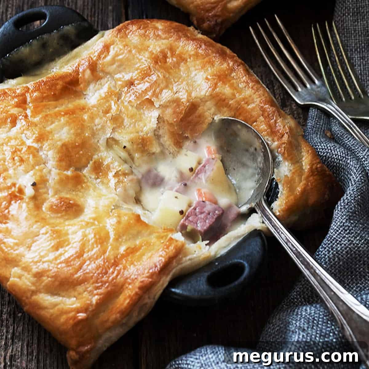 Individual Cabbage and Corned Beef Pot Pies baked in small cast iron skillets, ready to be served with a spoon.