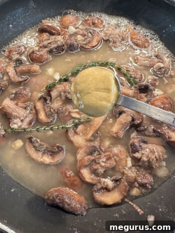 Adding Dijon mustard to the simmering sauce in the pan