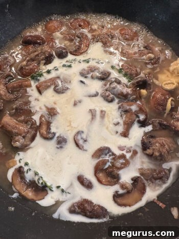 Pouring heavy cream into the sauce in the skillet