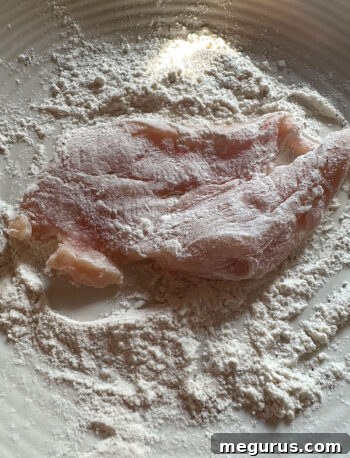 Chicken pieces being coated in seasoned flour