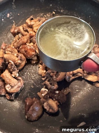 Adding chicken broth to the pan with mushrooms and aromatics