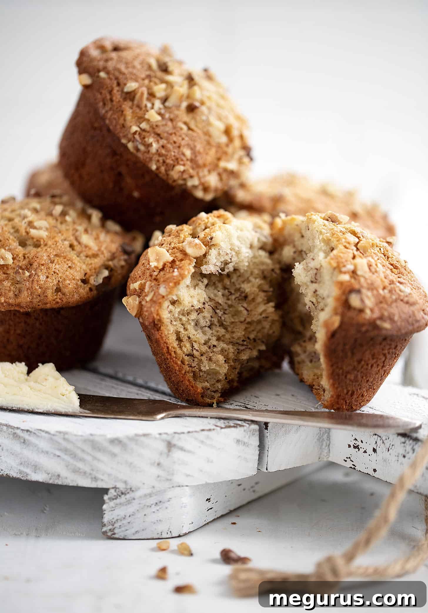 Two banana walnut muffins artfully placed on a white serving platter, showcasing their golden crust and walnut topping.