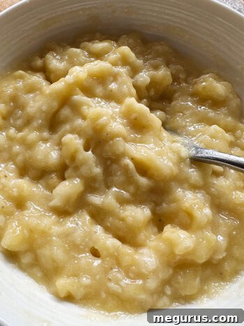 Mashed bananas in a bowl with a fork, showing a chunky yet smooth consistency.