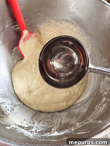 A scoop of finished banana walnut muffin batter in a mixing bowl, ready for portioning.