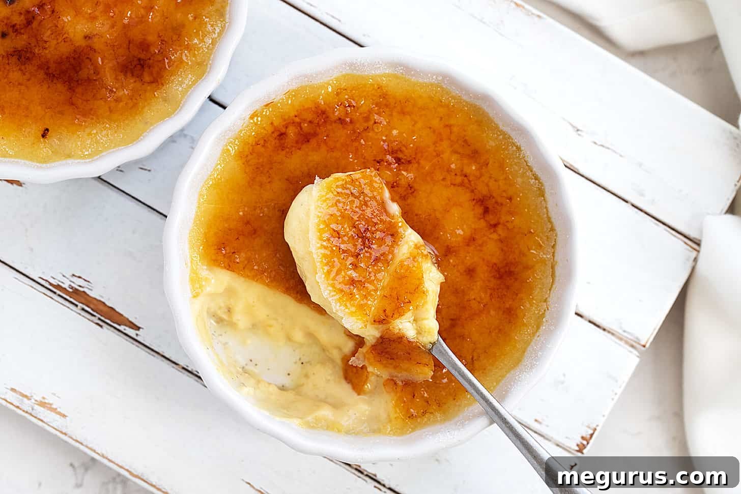 Silky smooth maple Crème Brûlée in a ramekin with a spoon, highlighting the torched sugar topping