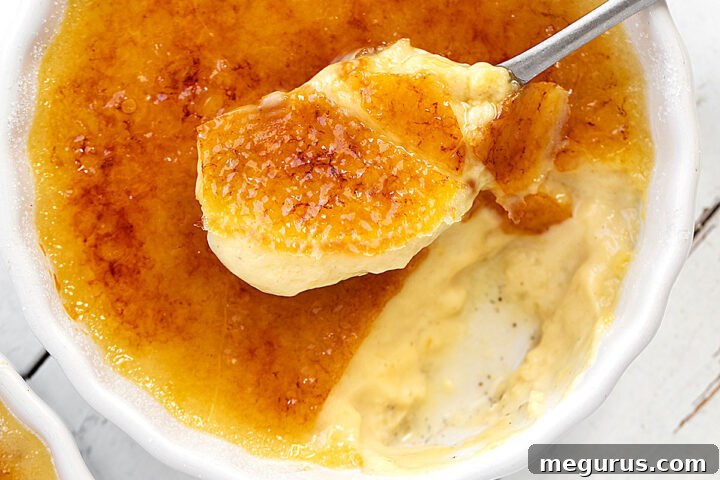 Maple Crème Brûlée in a ramekin with a spoon, showing the creamy texture and torched sugar