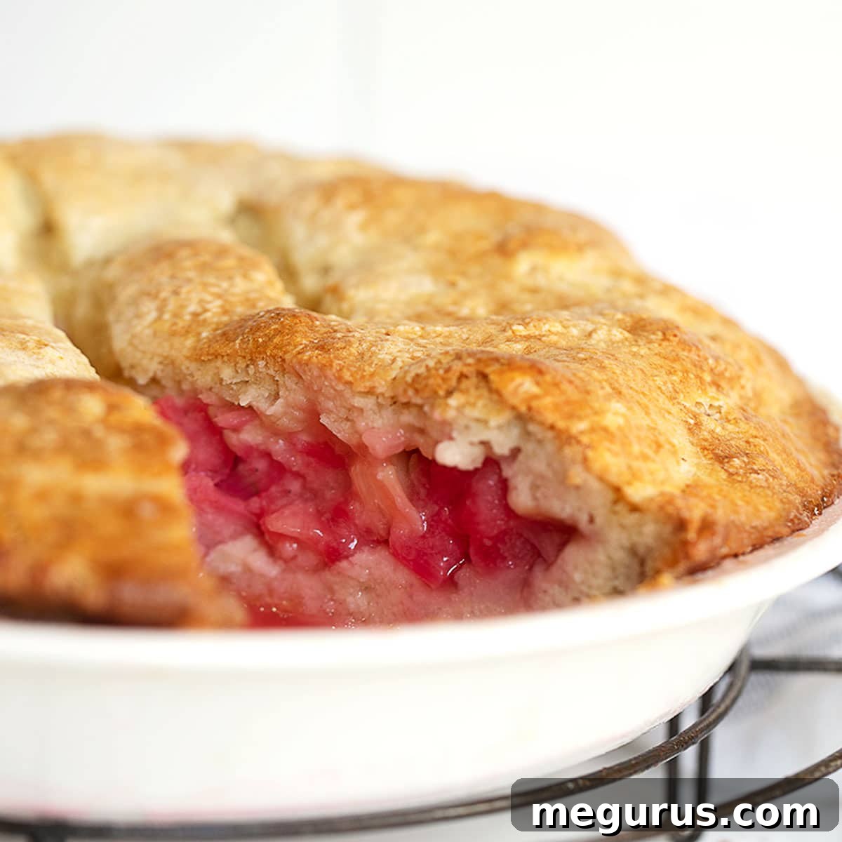 A rustic rhubarb pie cake, served in a pan with a slice removed.