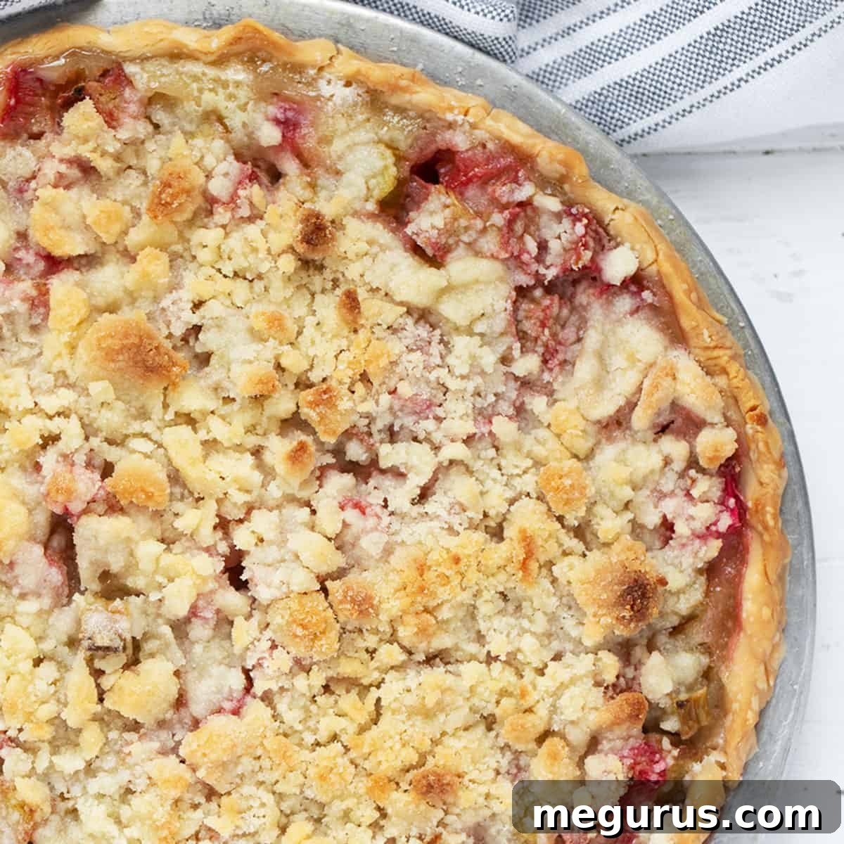 A rhubarb crumble pie in a pie plate, ready to be served.