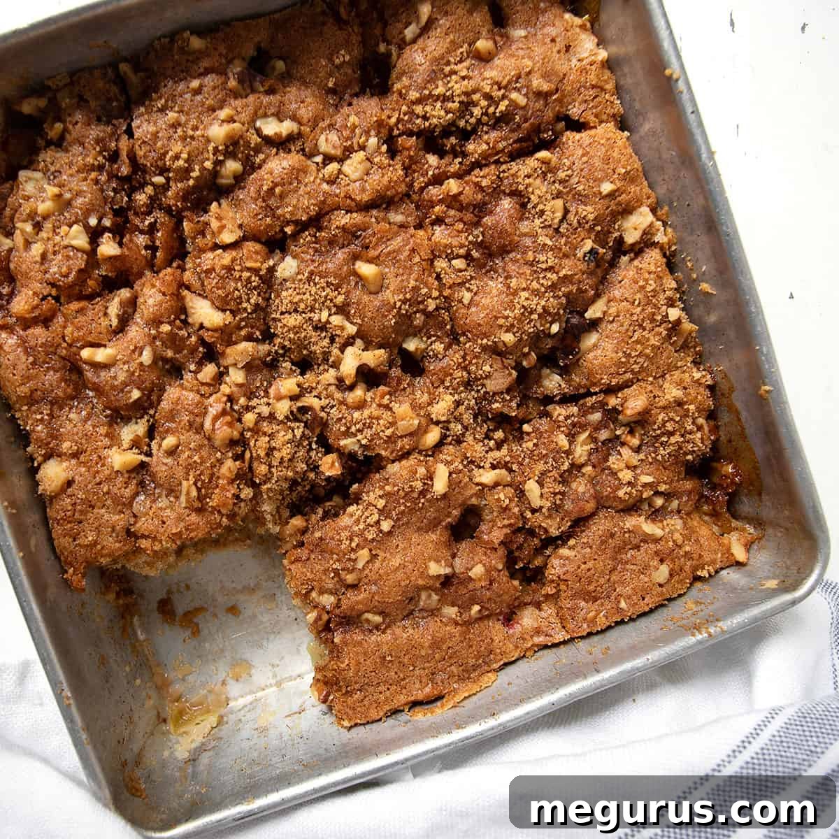An old-fashioned rhubarb cake in a baking pan with a slice removed.