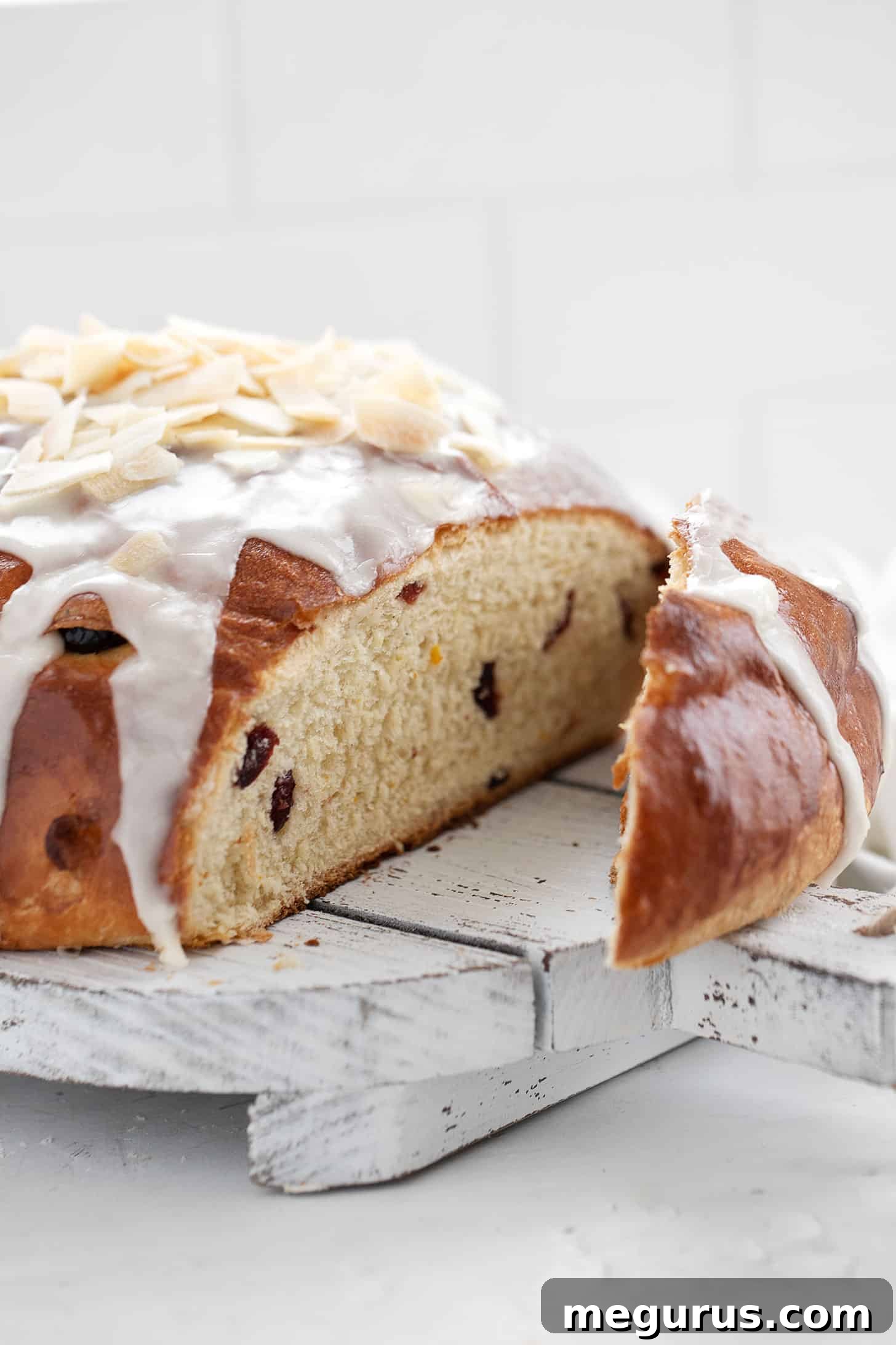 Close-up of a generous slice of cranberry orange yeast bread on a wooden cutting board, highlighting the soft crumb and cranberry pieces.