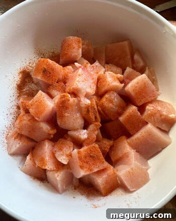 cubed chicken marinating in small bowl