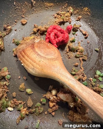 adding tomato paste to skillet