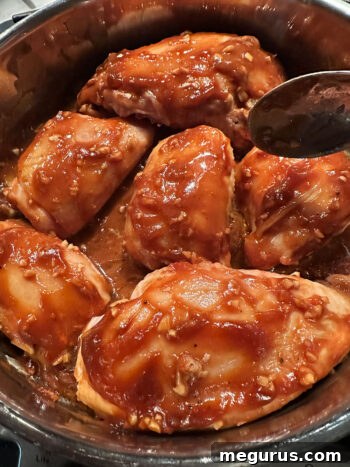 Basting sticky chicken with the pan glaze during oven baking.