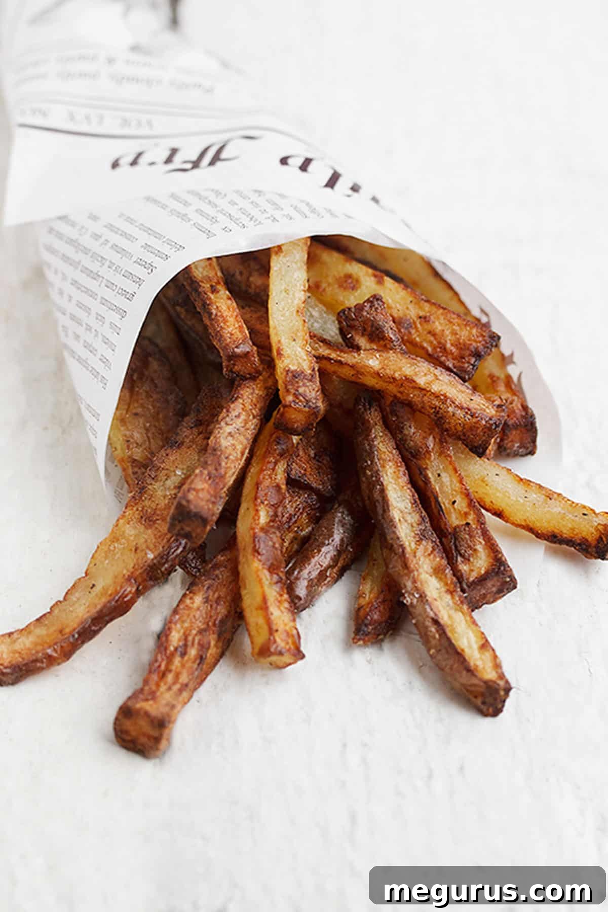 close up of air fryer fries wrapped in newspaper wrap, showing texture
