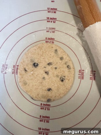 A dough ball being rolled out into a flat, circular breakfast round.