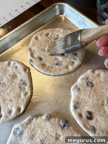 Shaped dough rounds placed on a baking sheet and brushed lightly with water.