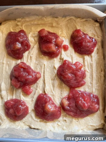 Spoonfuls of rhubarb compote placed on top of blondie batter