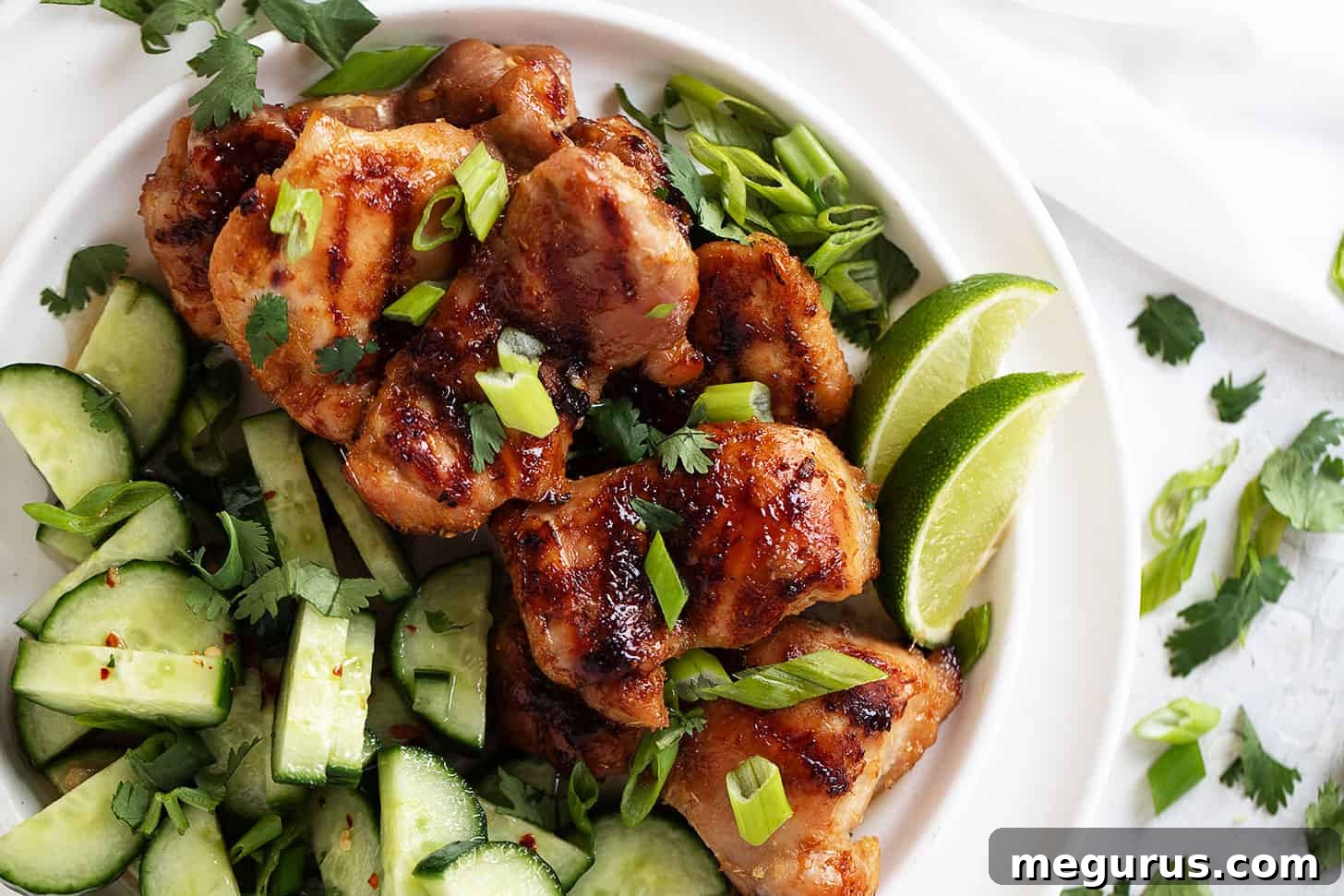 Perfectly grilled lemongrass chicken thighs served on a white plate with fresh herbs.